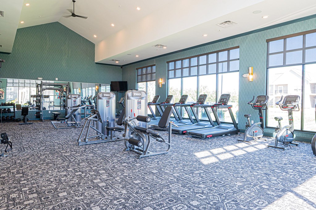 A gym with a variety of equipment including treadmills, weights, and exercise bikes.