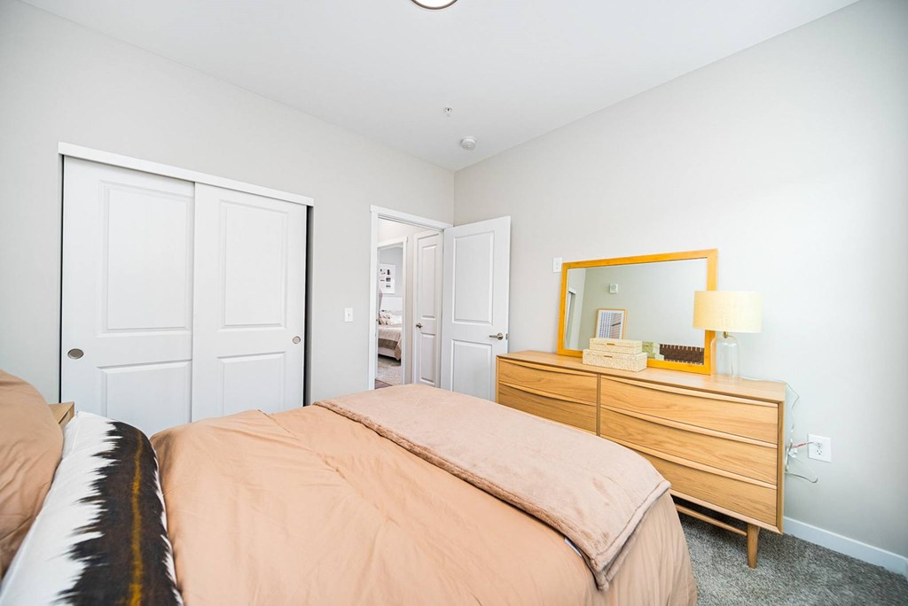 A bedroom with a bed, dresser, and mirror.