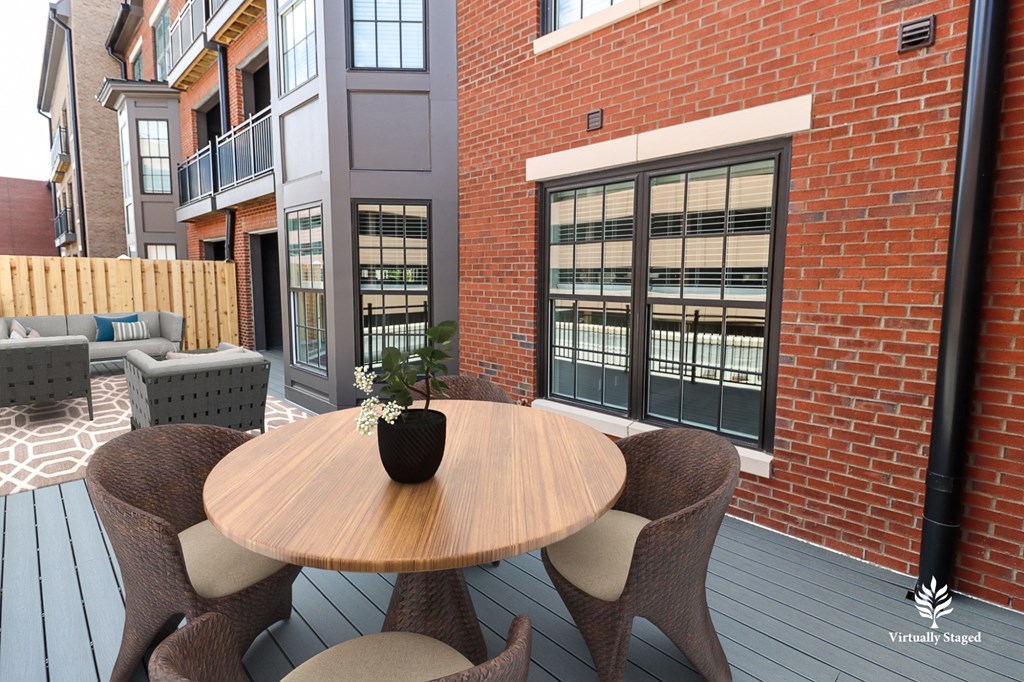 a patio with a table and chairs in front of a brick building