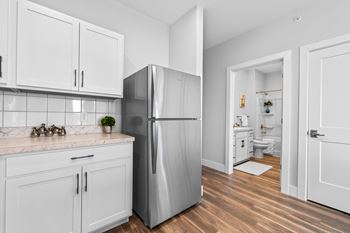 A kitchen with white cabinets and a stainless steel refrigerator.