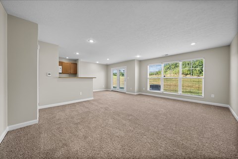 A spacious room with carpeted floor and large windows.