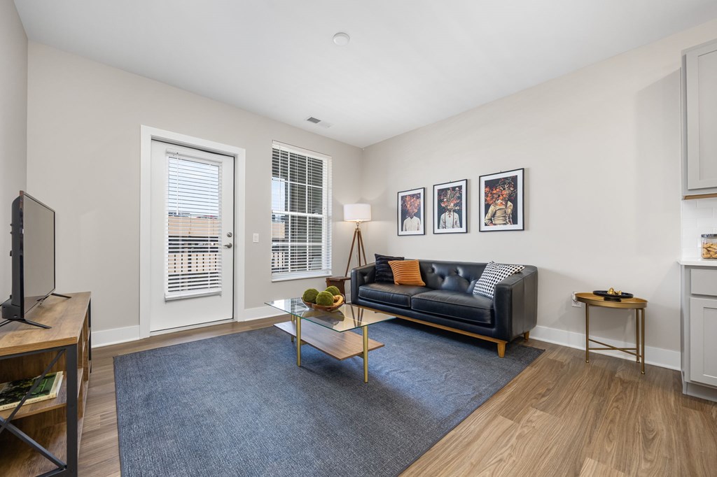 A living room with a black couch, a coffee table, and a TV.