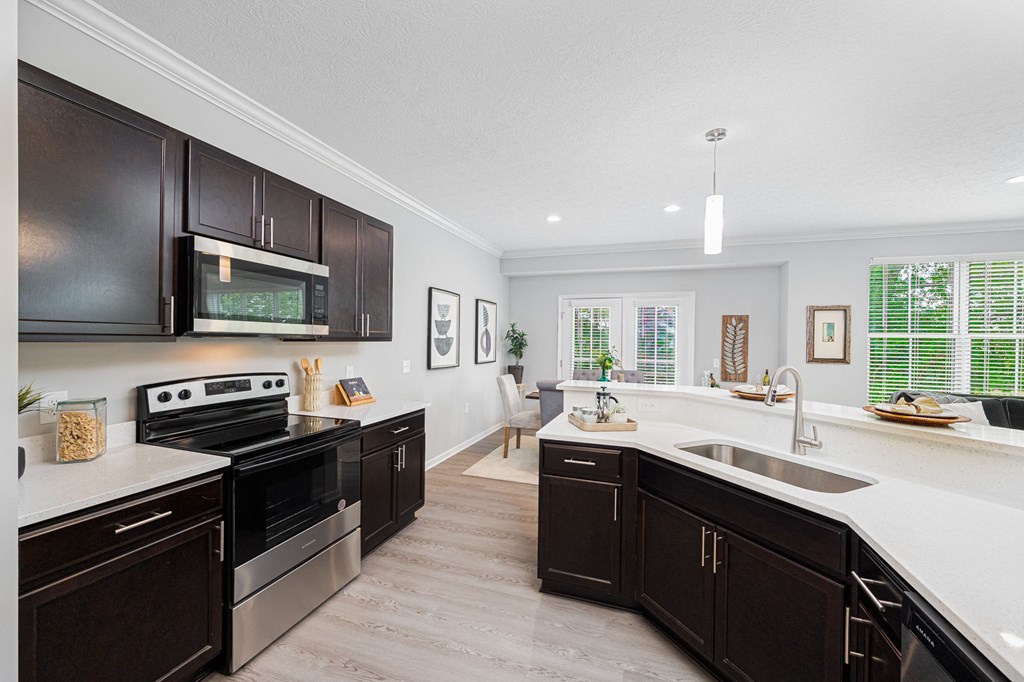 a large kitchen with black cabinets and white counter tops and a sink