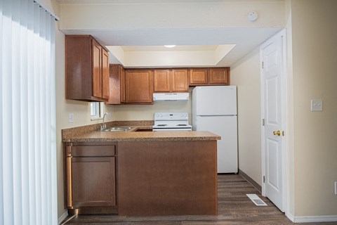 A kitchen with brown cabinets and a white refrigerator.