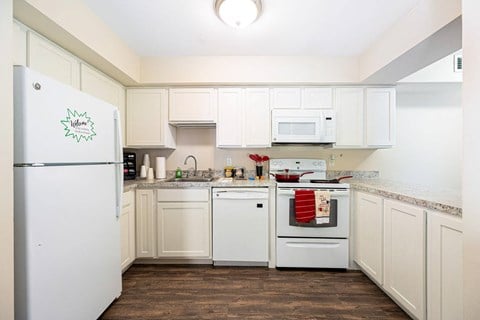 a kitchen with white cabinets and appliances and a white refrigerator