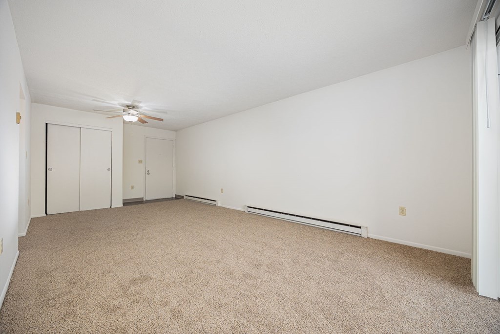 A room with a carpet floor and a ceiling fan.