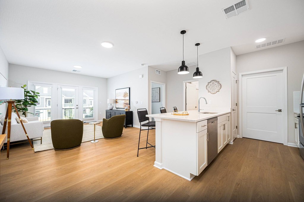 A modern kitchen with white cabinets and a wooden floor.