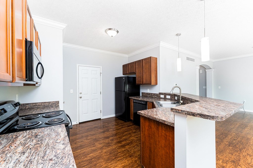 A kitchen with a black stove top oven and a black refrigerator.