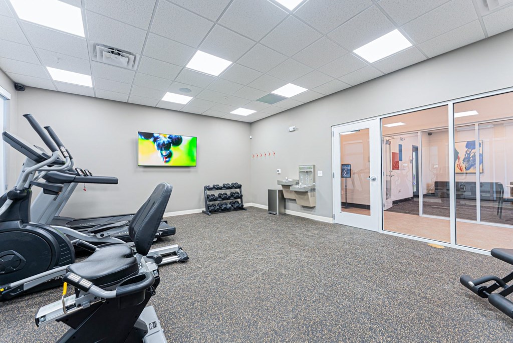 A gym room with treadmills and a television.