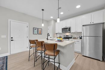 A kitchen with white cabinets and a stainless steel refrigerator.