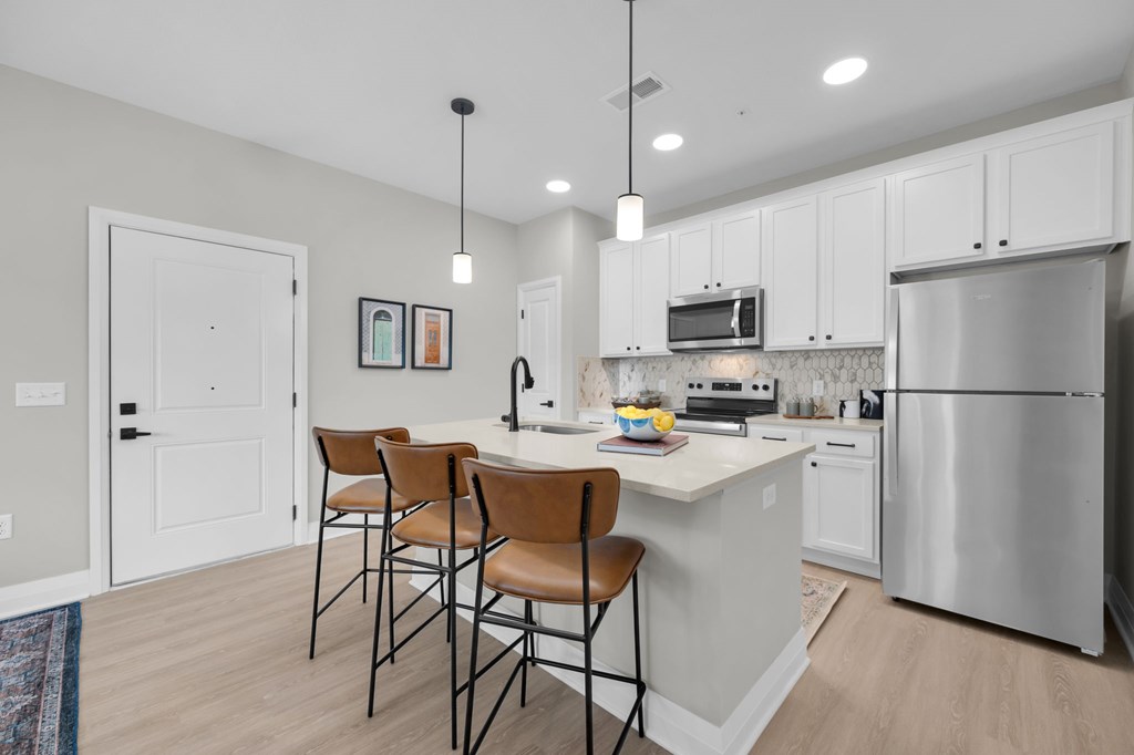 A kitchen with white cabinets and a stainless steel refrigerator.