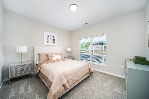 A bedroom with a large bed and a window with blinds.