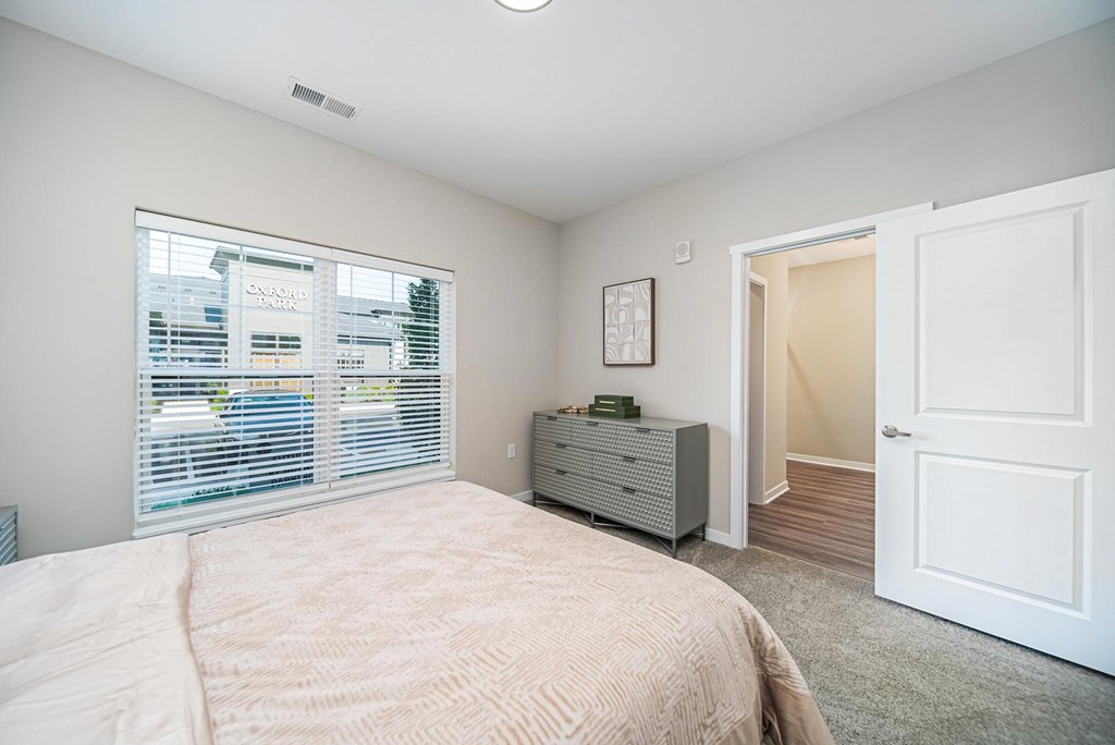 A bedroom with a bed, dresser, and window.