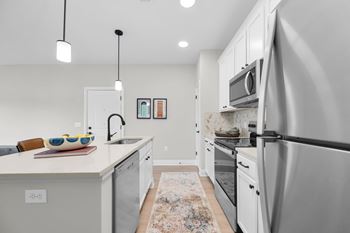 A modern kitchen with a white countertop and stainless steel appliances.
