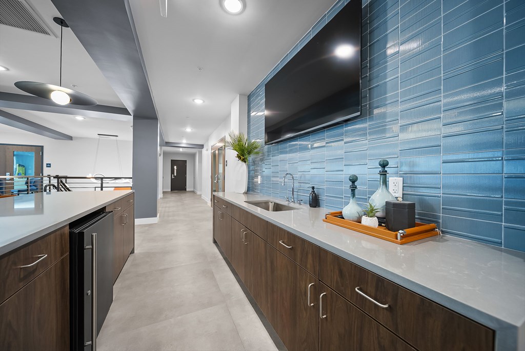 A modern kitchen with wooden cabinets and a blue tiled backsplash.