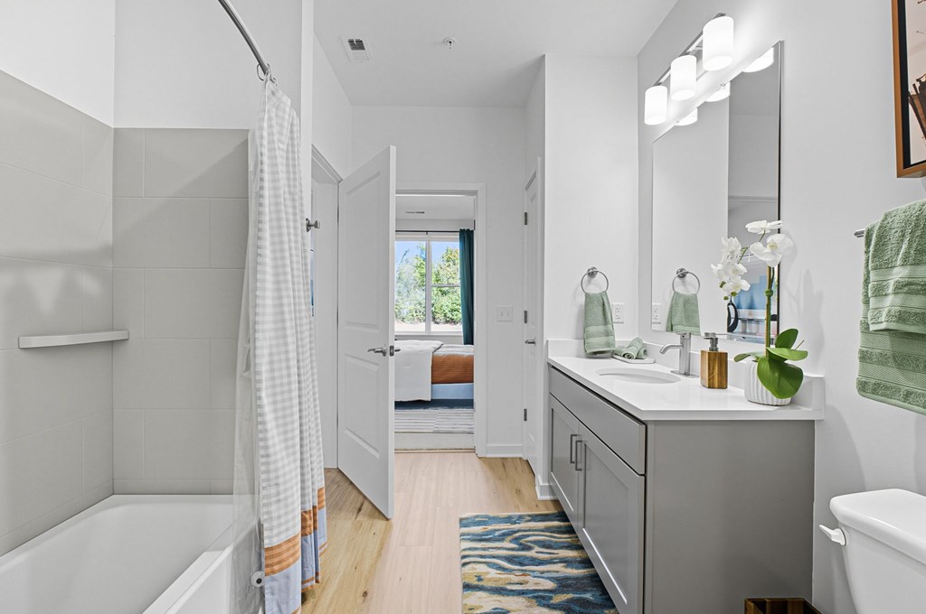 A bathroom with a white tub, sink, and a mirror.