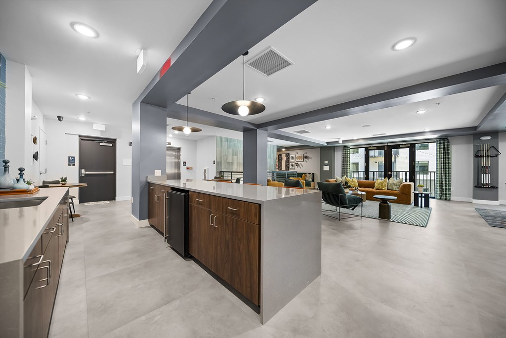 A modern kitchen with a large island and a living area with a couch and chairs.