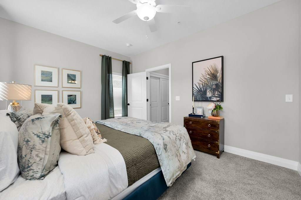 A bedroom with a bed, dresser, and a ceiling fan.