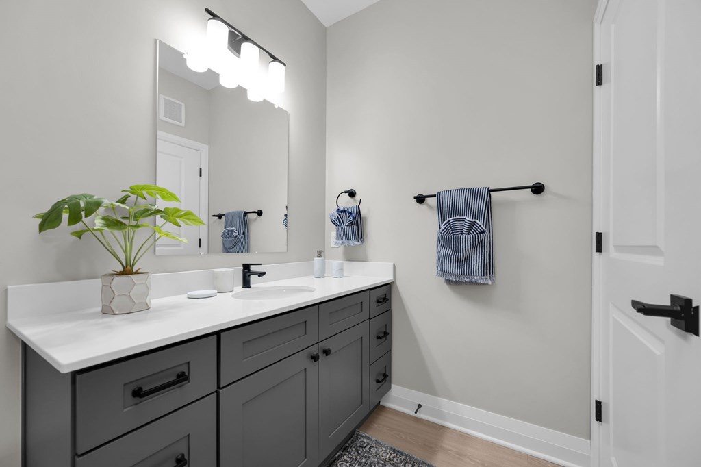 A bathroom with a white counter top and a mirror above it.