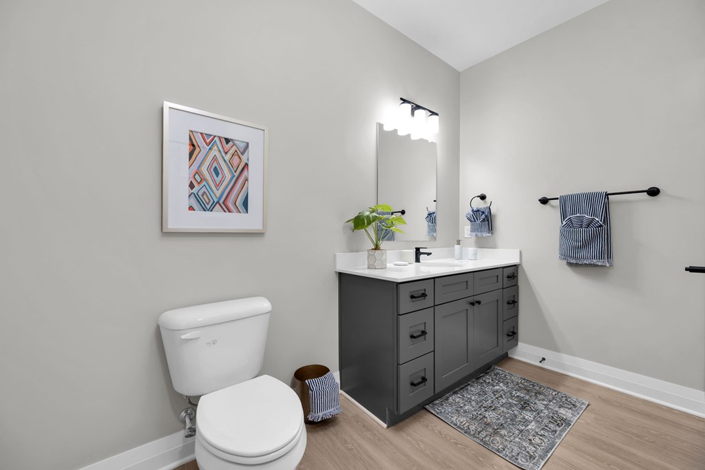 A bathroom with a white toilet and a framed picture on the wall.