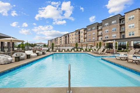 A large swimming pool in front of apartment buildings.