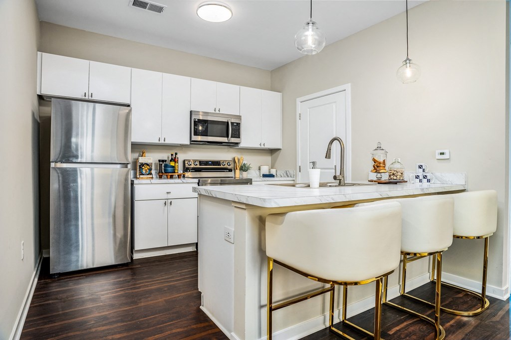 a kitchen with white cabinets and a counter top and a stainless steel refrigerator