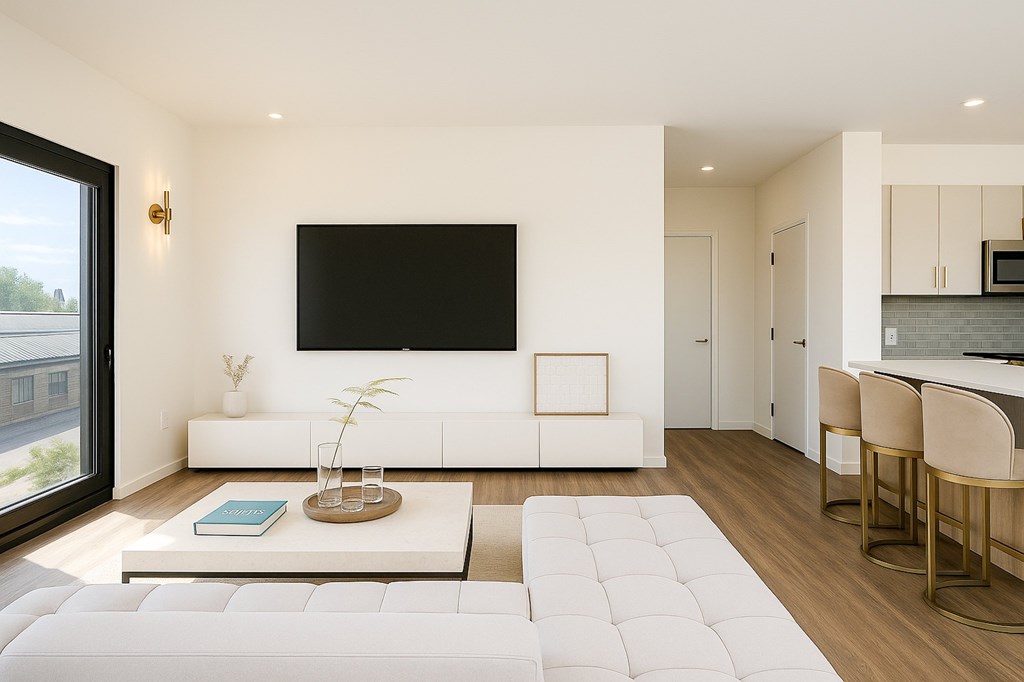 A modern living room with a large white couch and a flat screen TV mounted on the wall.