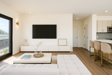 A modern living room with a large white couch and a flat screen TV mounted on the wall.