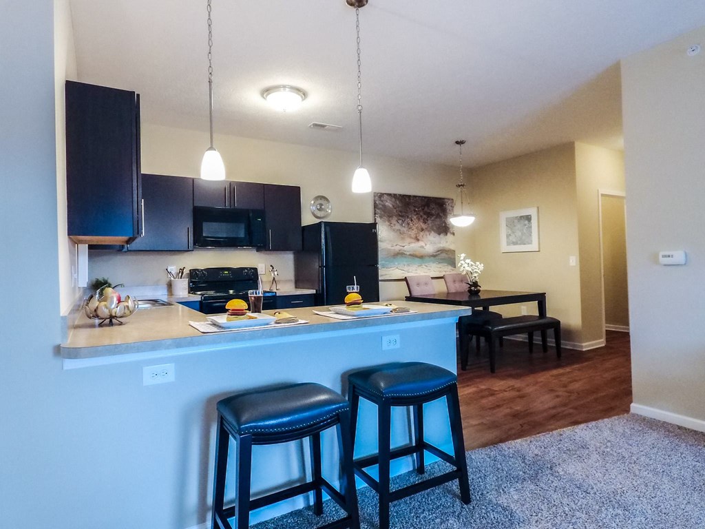 a kitchen with a breakfast bar and a dining room in the background