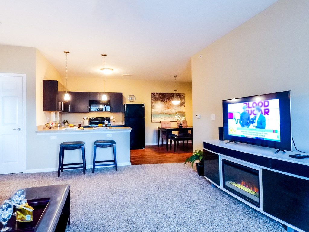 a living room with a flat screen tv and a kitchen in the background