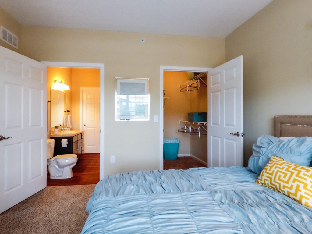 a bedroom with a bed and a bathroom in the background