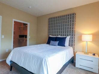 a bedroom with a white bed and a white nightstand with a lamp