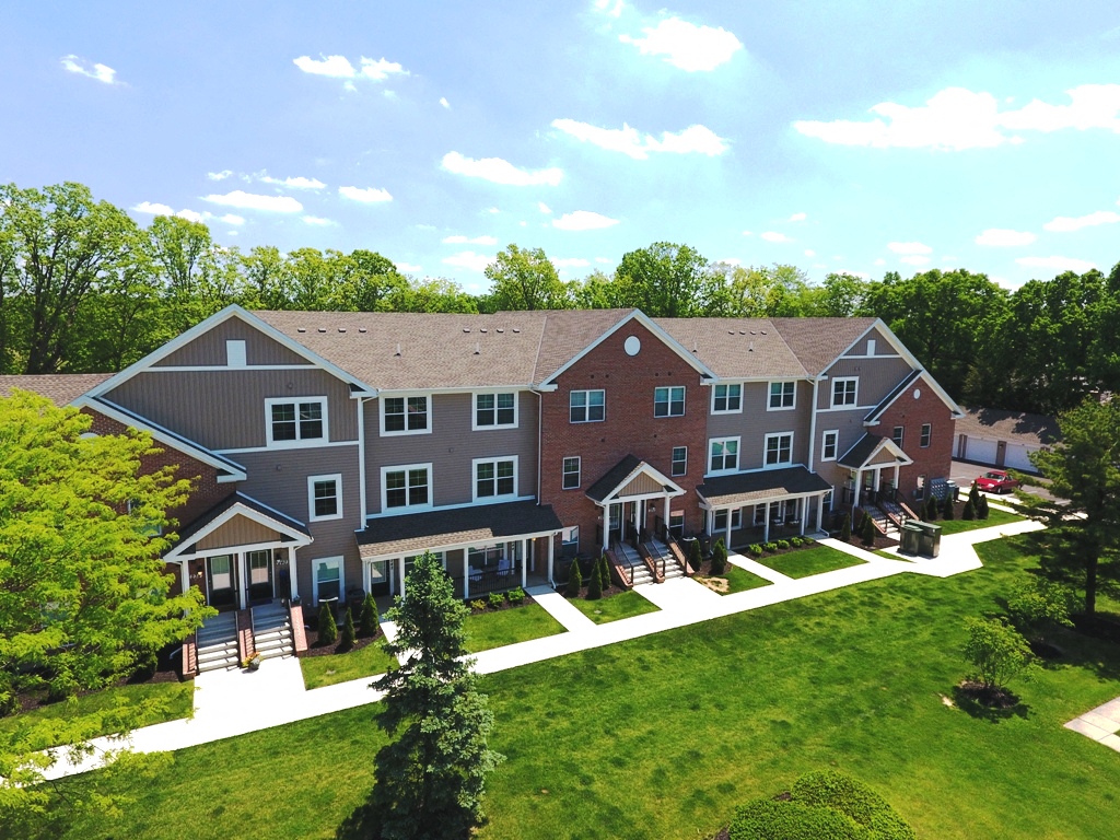 an aerial view of a large building with a green lawn and trees