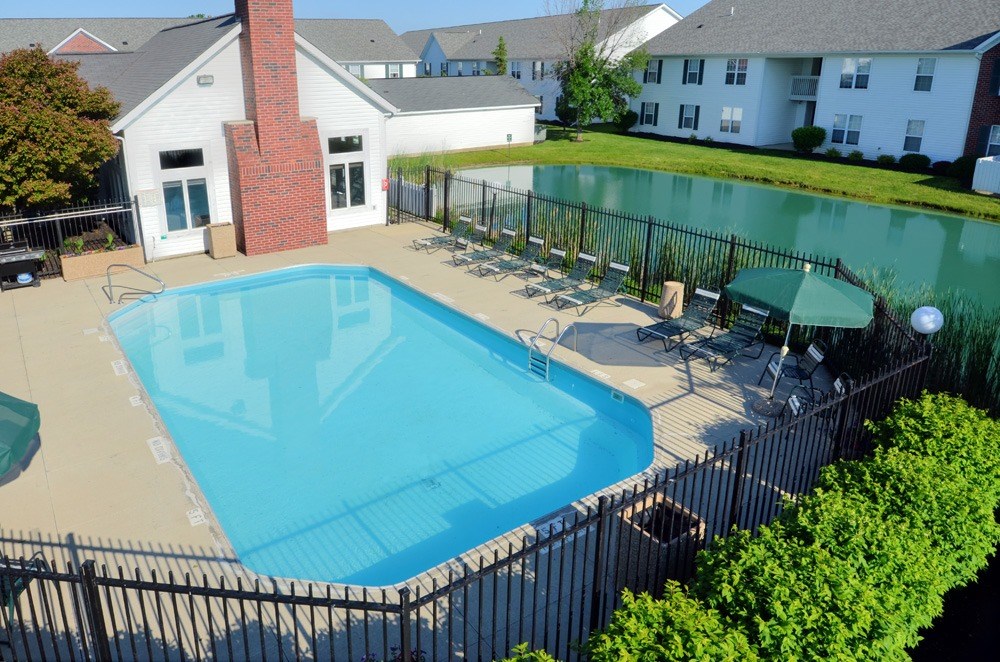 A black fence surrounds a blue swimming pool.