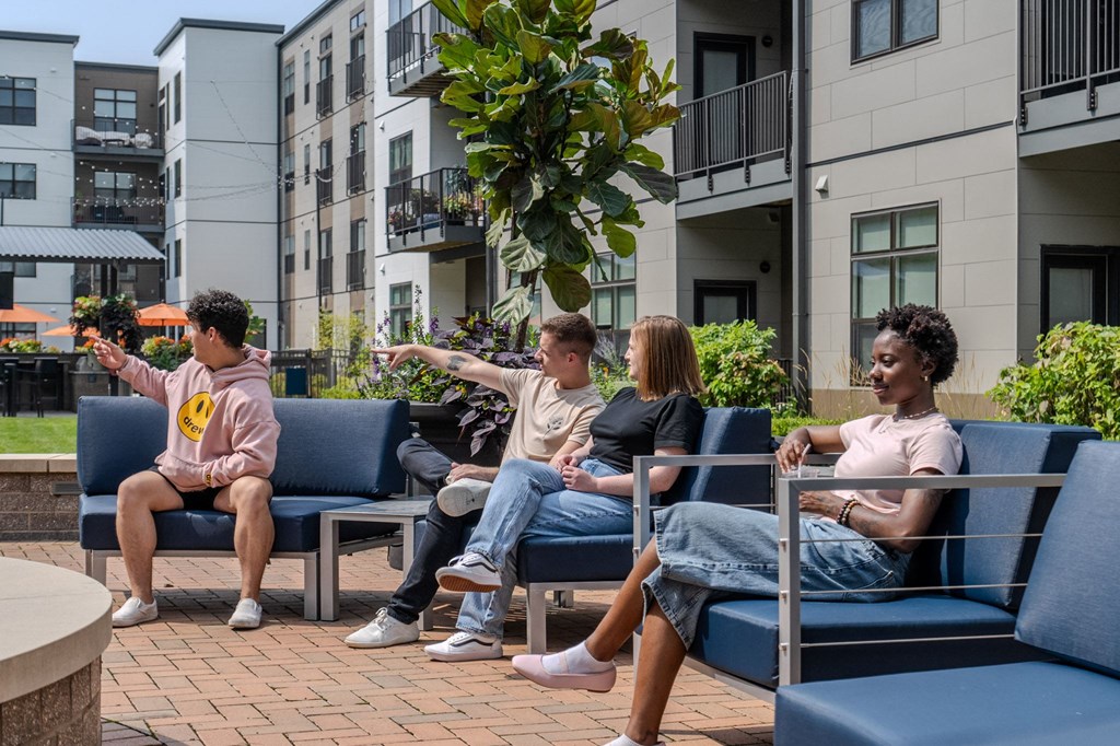 a group of people sitting on blue chairs in a courtyard