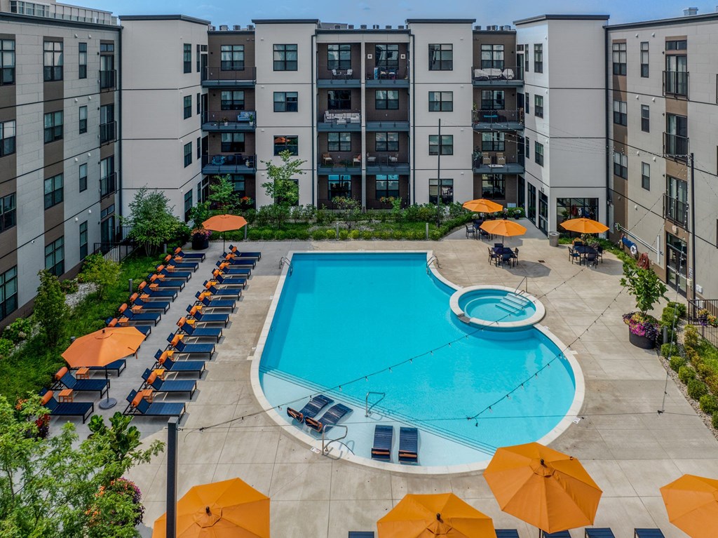 an aerial view of an apartment pool with umbrellas and lounge chairs around it