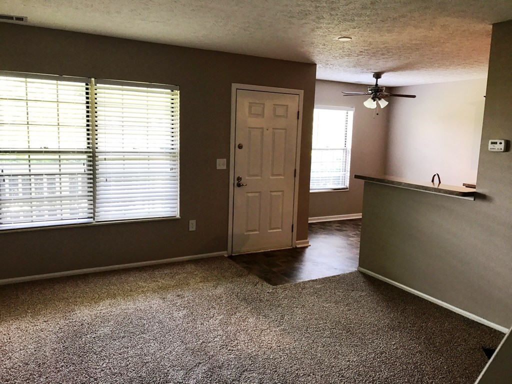 an empty living room with a white door and window