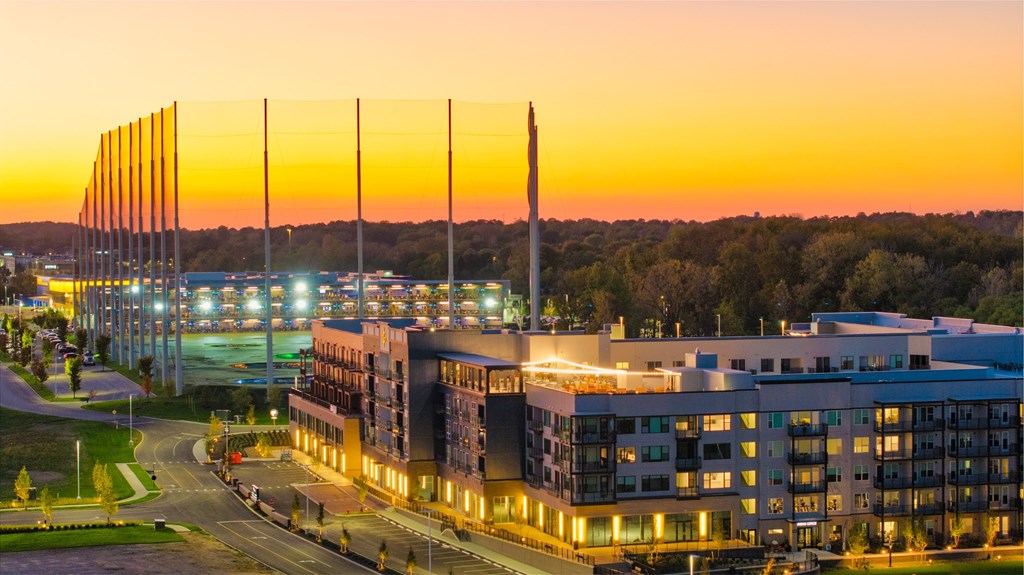 A modern building with a parking lot in front of it during sunset.