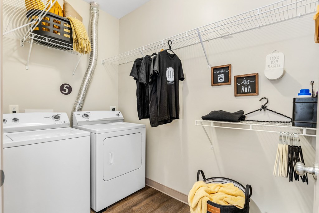 a washer and dryer in a laundry room with clothes hanging on the wall