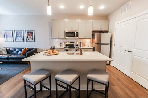 a kitchen with a large island with three stools in front of it