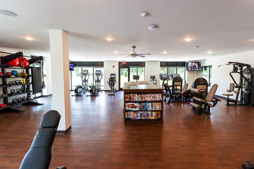 a room with a lot of exercise equipment and a bookcase full of dvds