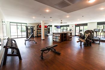 a workout room with weights and other exercise equipment in a large room with windows