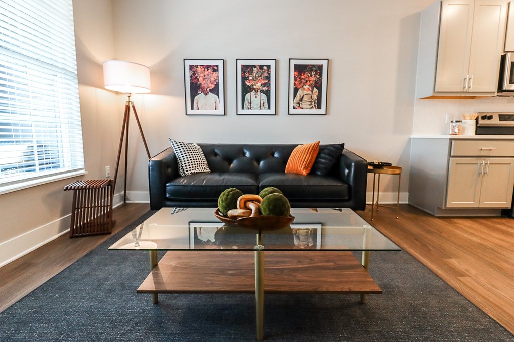 a living room with a black couch and a glass coffee table