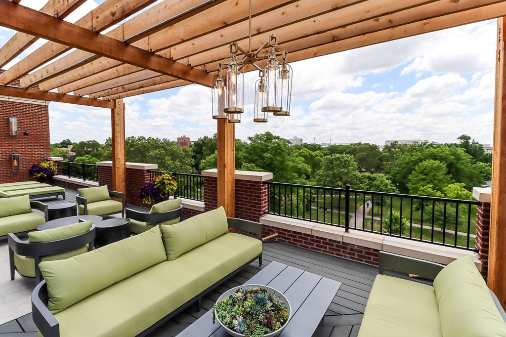 a covered patio with green couches and a chandelier