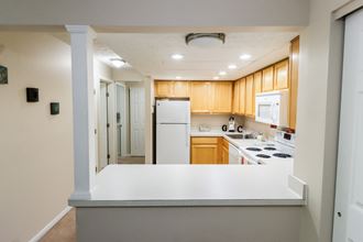 an empty kitchen with a white counter top and a refrigerator