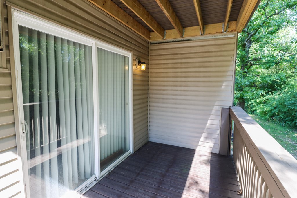 a covered porch with sliding glass doors and a wooden deck
