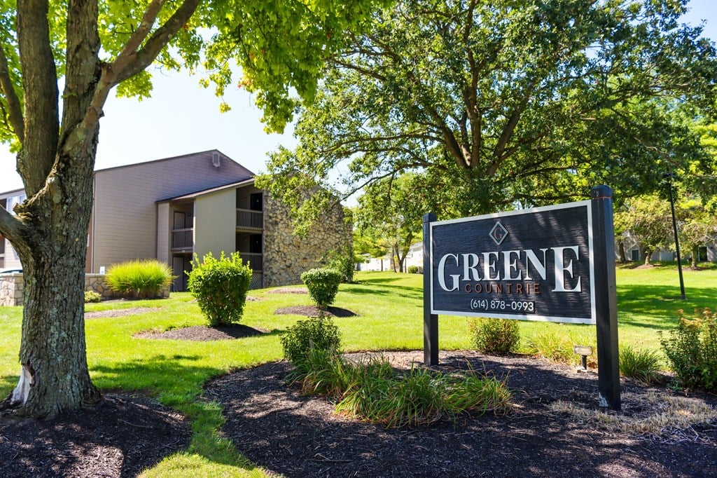 a sign that says greene apartments with a building in the background