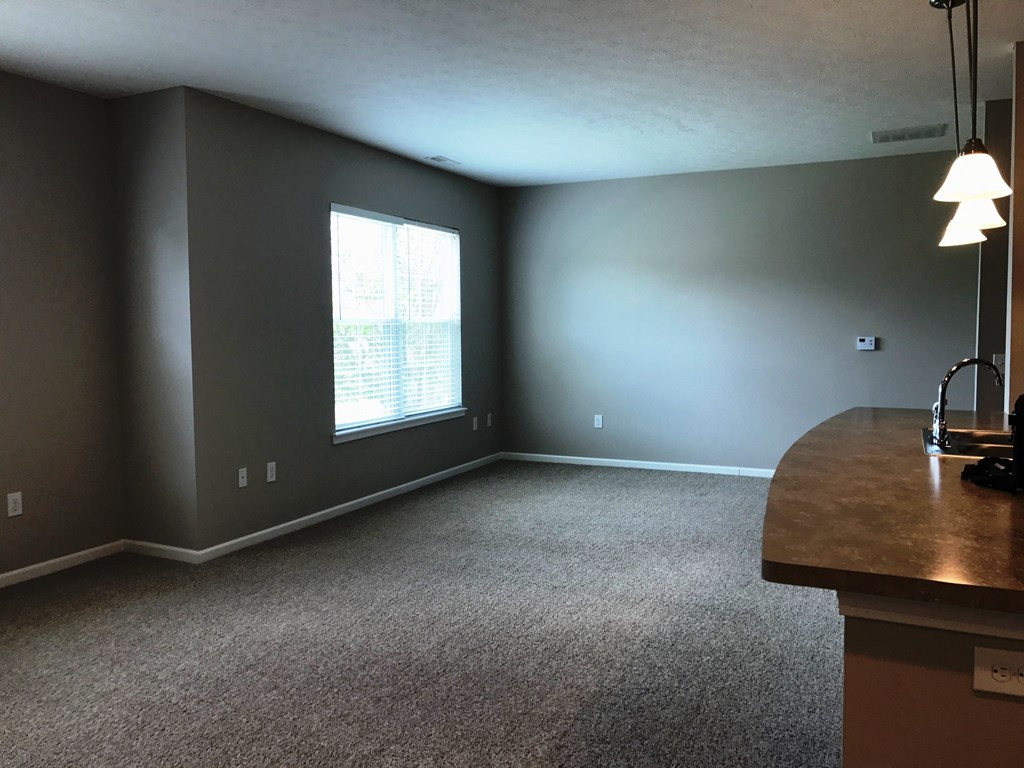 an empty living room with gray walls and a window
