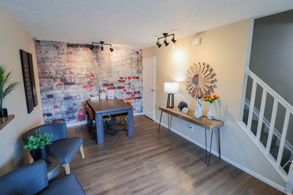 a living room with an exposed brick wall and a dining room table