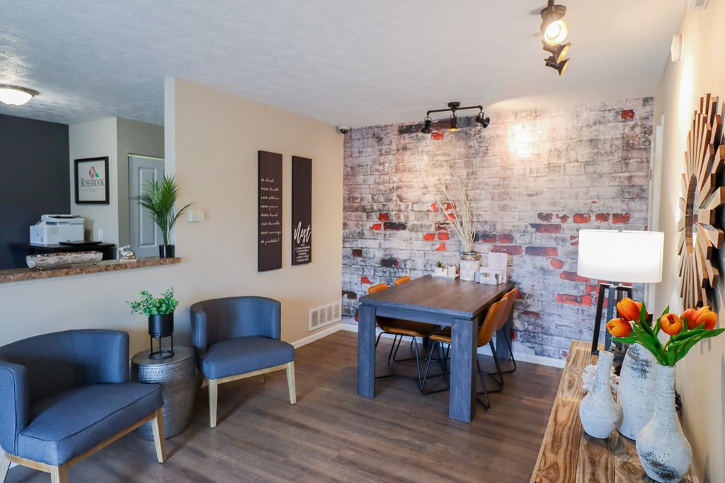 a living room with a table and chairs and a brick wall